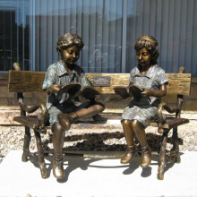 двое детей сидят на скамейке и читает бронзовая статуя скульптура